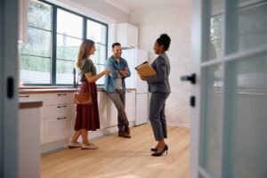 A couple reviews documents around a dining table, comparing expenses for renting and buying a house.