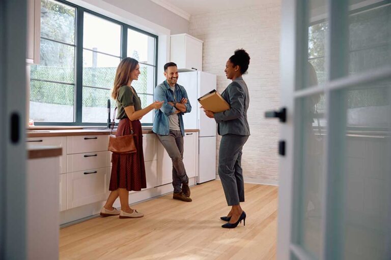 A couple reviews documents around a dining table, comparing expenses for renting and buying a house.